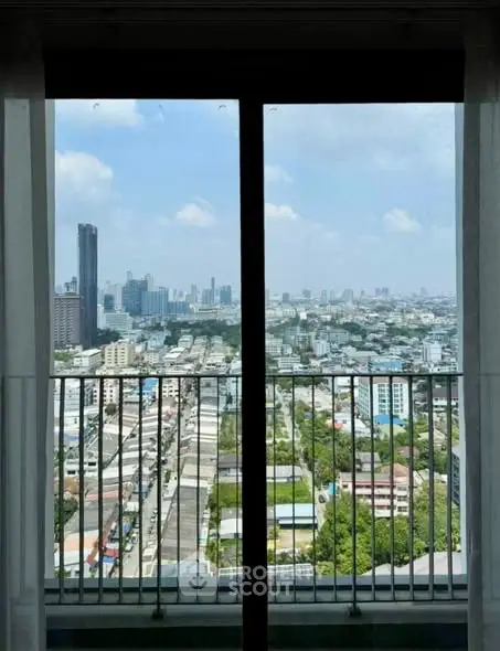 Stunning cityscape view from high-rise balcony with clear blue sky.
