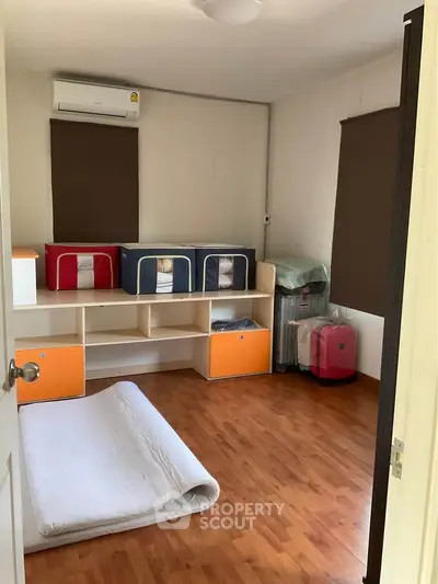 Cozy bedroom with wooden flooring and ample storage space, perfect for a comfortable living experience.