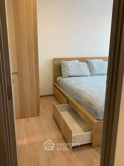 Cozy bedroom with wooden flooring and modern bed featuring built-in storage drawers.