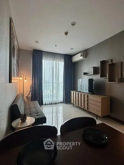 Modern living room with sleek furniture and large window offering natural light.