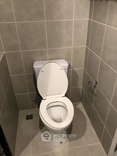 Compact bathroom with modern tiled walls and floor featuring a standard toilet.