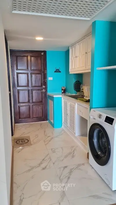 Modern kitchen with washing machine and vibrant turquoise walls