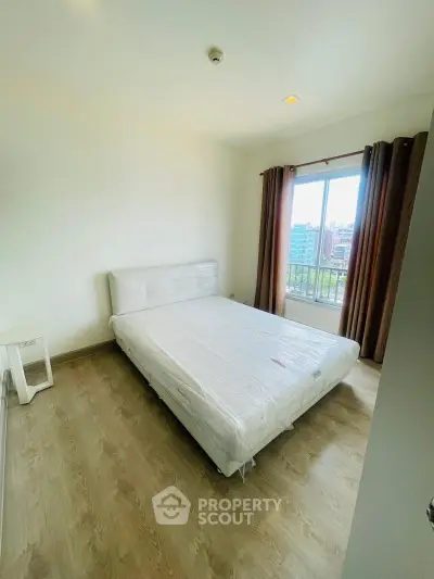 Bright bedroom with large window and wooden flooring in modern apartment