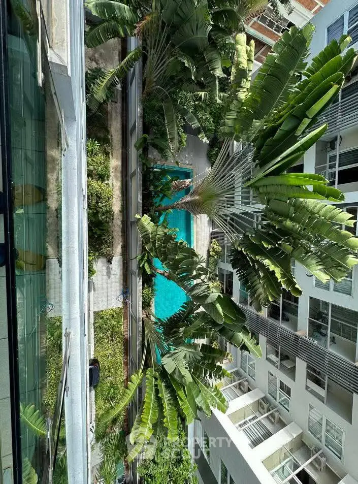 Stunning aerial view of modern apartment complex with lush greenery and inviting swimming pool.