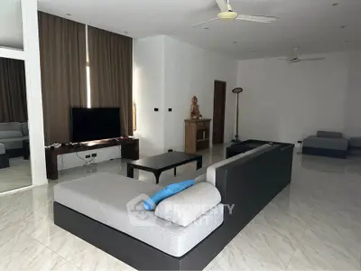 Spacious modern living room with sleek furniture and large windows, perfect for relaxation and entertainment.