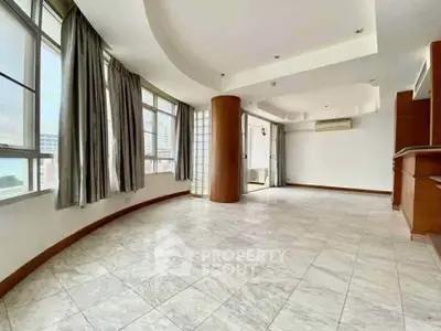 Spacious living room with large windows and elegant tile flooring in modern apartment.