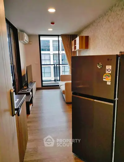 Modern living room with balcony view and sleek appliances in a stylish apartment.