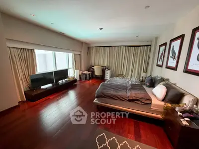 Spacious bedroom with hardwood floors and large windows in modern apartment