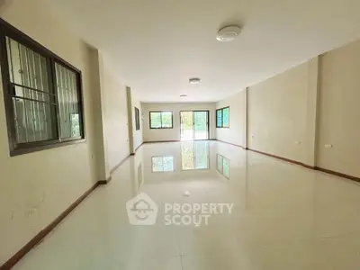 Spacious empty living room with large windows and glossy tiled floors, perfect for customization.