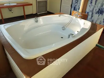 Luxurious bathroom with a spacious bathtub and elegant wooden accents, perfect for relaxation.