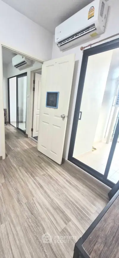 Modern apartment interior with air conditioning and sliding glass door to balcony.