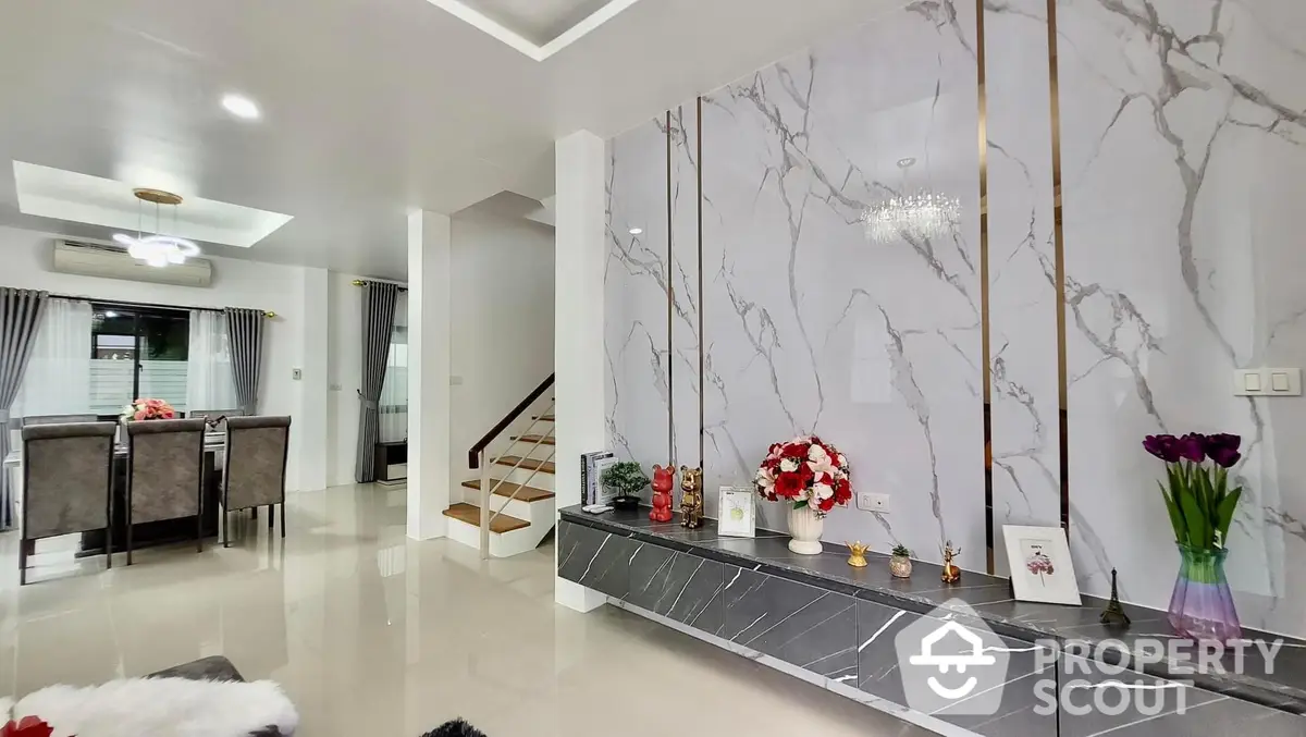 Elegant living space with polished marble floors and a grand staircase, accented by chic decor and a spacious layout, perfect for upscale living.