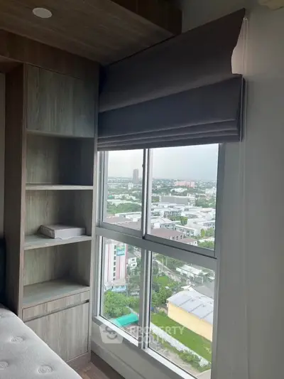 Modern bedroom with large window offering panoramic city view and built-in wooden shelving.