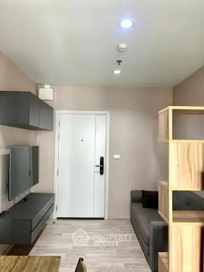 Modern living room with sleek furniture and neutral tones, featuring a wall-mounted TV and stylish shelving.