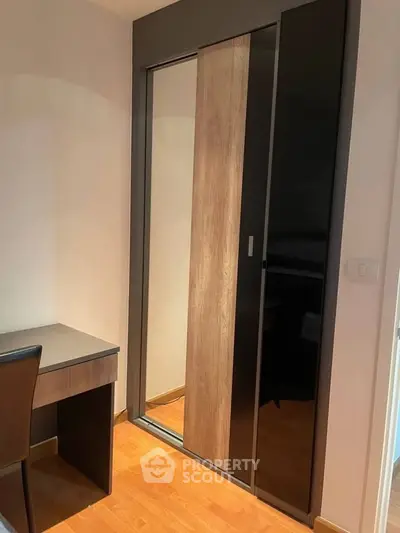 Modern bedroom with sleek sliding wardrobe and compact desk setup.