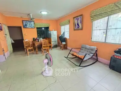 Spacious living room with vibrant orange walls, tiled floor, and cozy seating area.