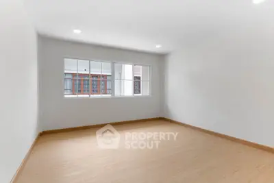 Spacious empty room with large window and wooden flooring, perfect for customization.