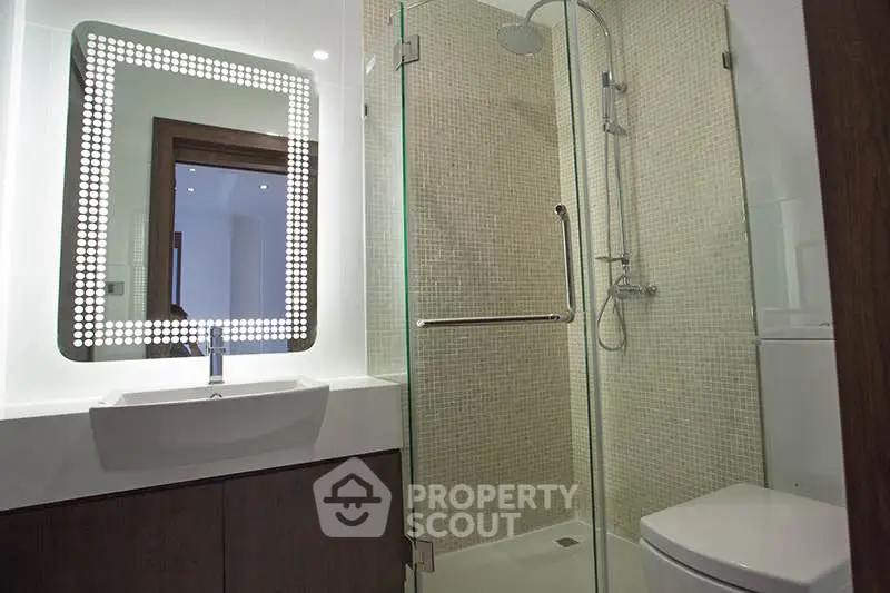 Modern bathroom with illuminated mirror and glass shower enclosure