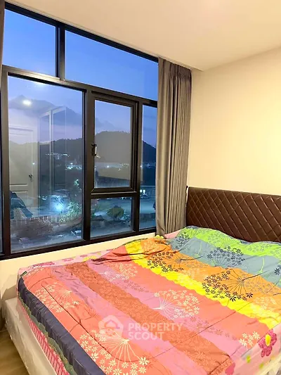 Cozy bedroom with large window offering scenic mountain view, vibrant bedding adds a splash of color.