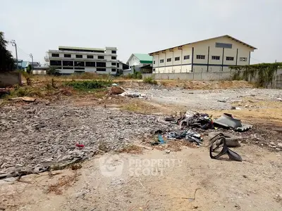 Vacant land plot with potential for development near industrial buildings.