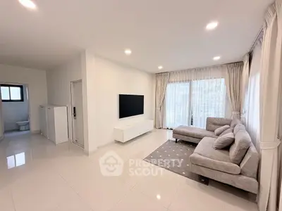 Spacious modern living room with large windows and elegant gray sofa