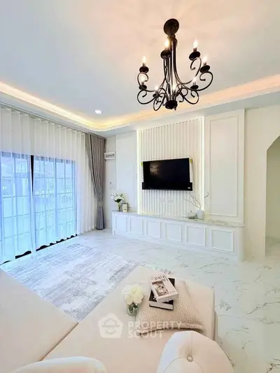 Elegant living room with chandelier and modern decor, featuring a large window and stylish furnishings.