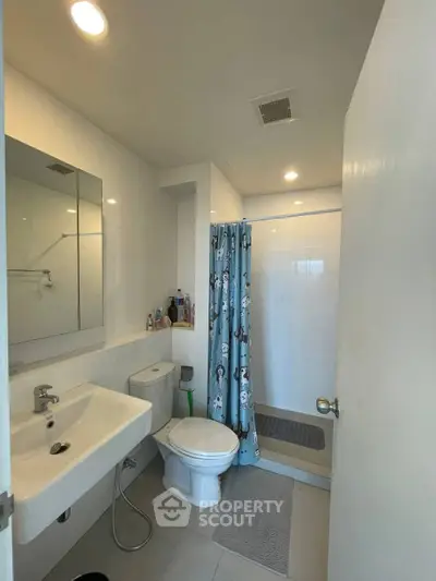 Modern bathroom with shower curtain and sleek fixtures in a contemporary apartment.