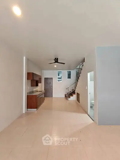 Spacious open-plan living area with modern kitchen and staircase, perfect for family gatherings.