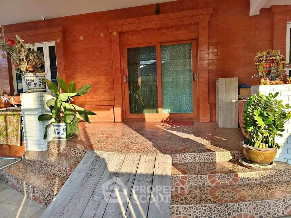 Charming entrance with decorative tiles and lush potted plants