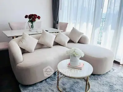 Elegant living room with plush sofa, chic coffee table, and dining area by large windows.
