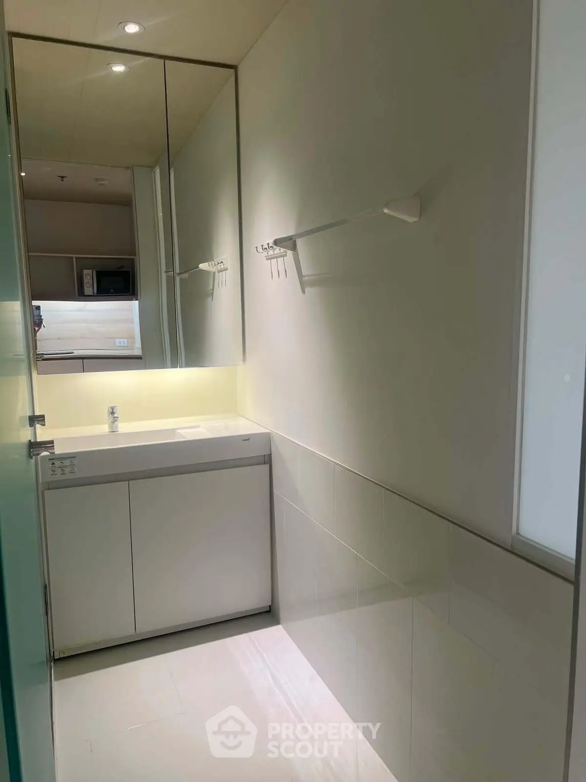 Modern bathroom with sleek design and ample lighting, featuring a large mirror and minimalist fixtures.