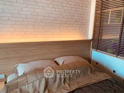 Cozy bedroom with modern design and warm lighting, featuring a stylish brick accent wall and wooden headboard.