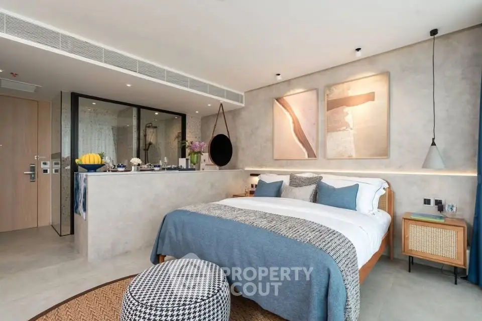 Modern bedroom with stylish decor and open bathroom layout, featuring cozy bedding and contemporary artwork.
