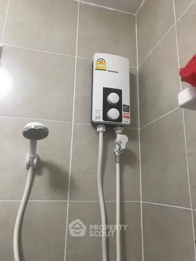 Modern bathroom with sleek shower fixture and water heater on tiled wall.