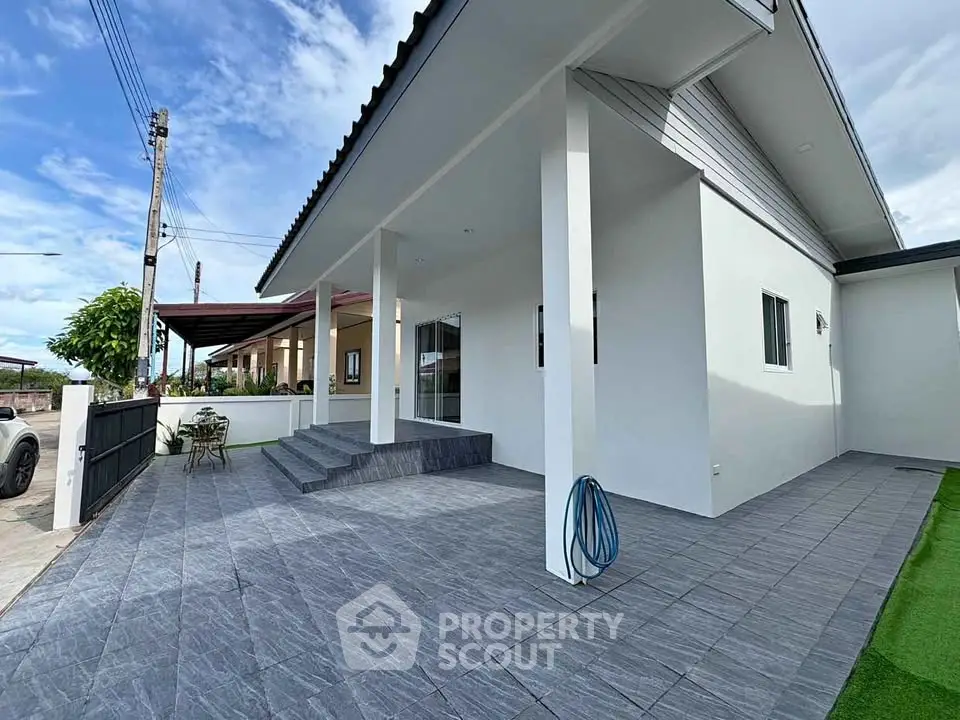 Modern single-story home with sleek exterior and spacious tiled patio, perfect for outdoor living.