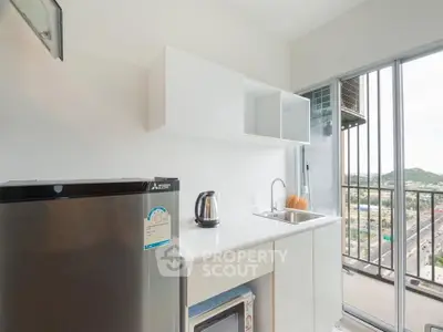 Modern kitchen with sleek appliances and balcony view in urban apartment