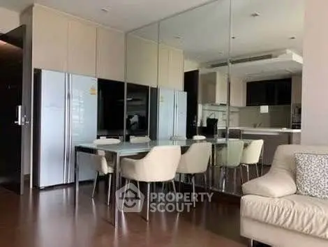 Modern dining area with mirrored wall and sleek kitchen in luxury apartment