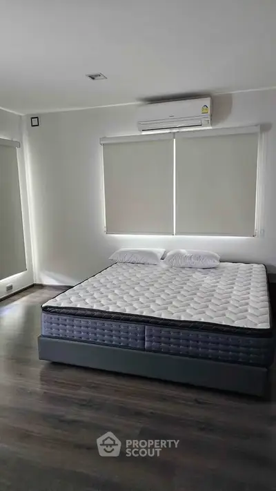 Spacious bedroom with modern decor and large windows for natural light.