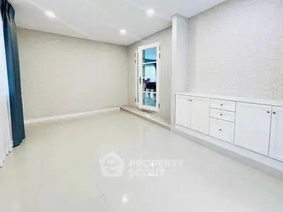 Spacious modern living room with elegant white cabinetry and sleek tiled flooring.
