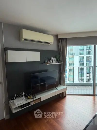 Modern living room with sleek TV setup and balcony view in urban apartment