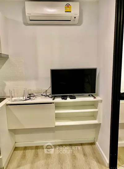 Modern living room with wall-mounted TV and air conditioning unit, featuring sleek storage shelves.