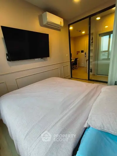 Modern bedroom with wall-mounted TV and air conditioning, featuring sliding glass doors to a study area.