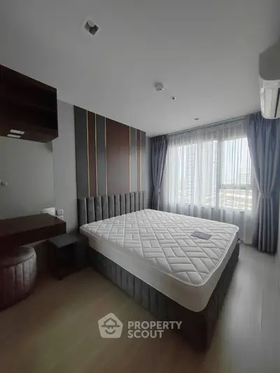 Spacious bedroom with modern decor and large window offering natural light