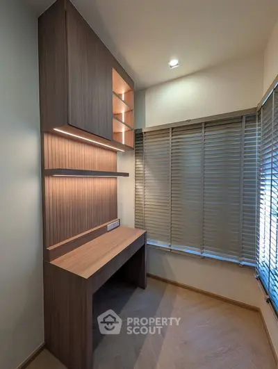 Modern study nook with built-in wooden desk and shelves, featuring ambient lighting and window blinds.