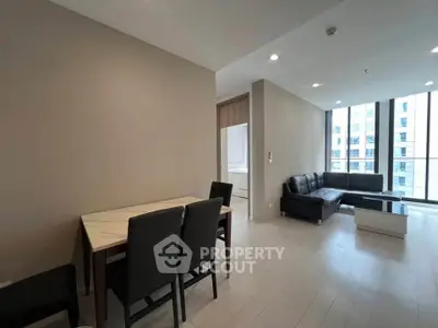 Modern living room with sleek furniture and large windows in a high-rise apartment.
