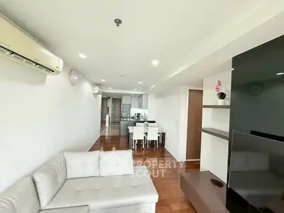 Spacious modern living room with sleek design and open layout, featuring a cozy white sofa and elegant dining area.