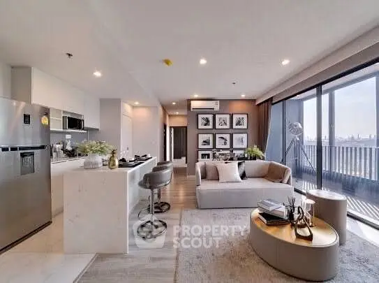 Modern open-plan living room with kitchen, stylish decor, and large balcony with city view.