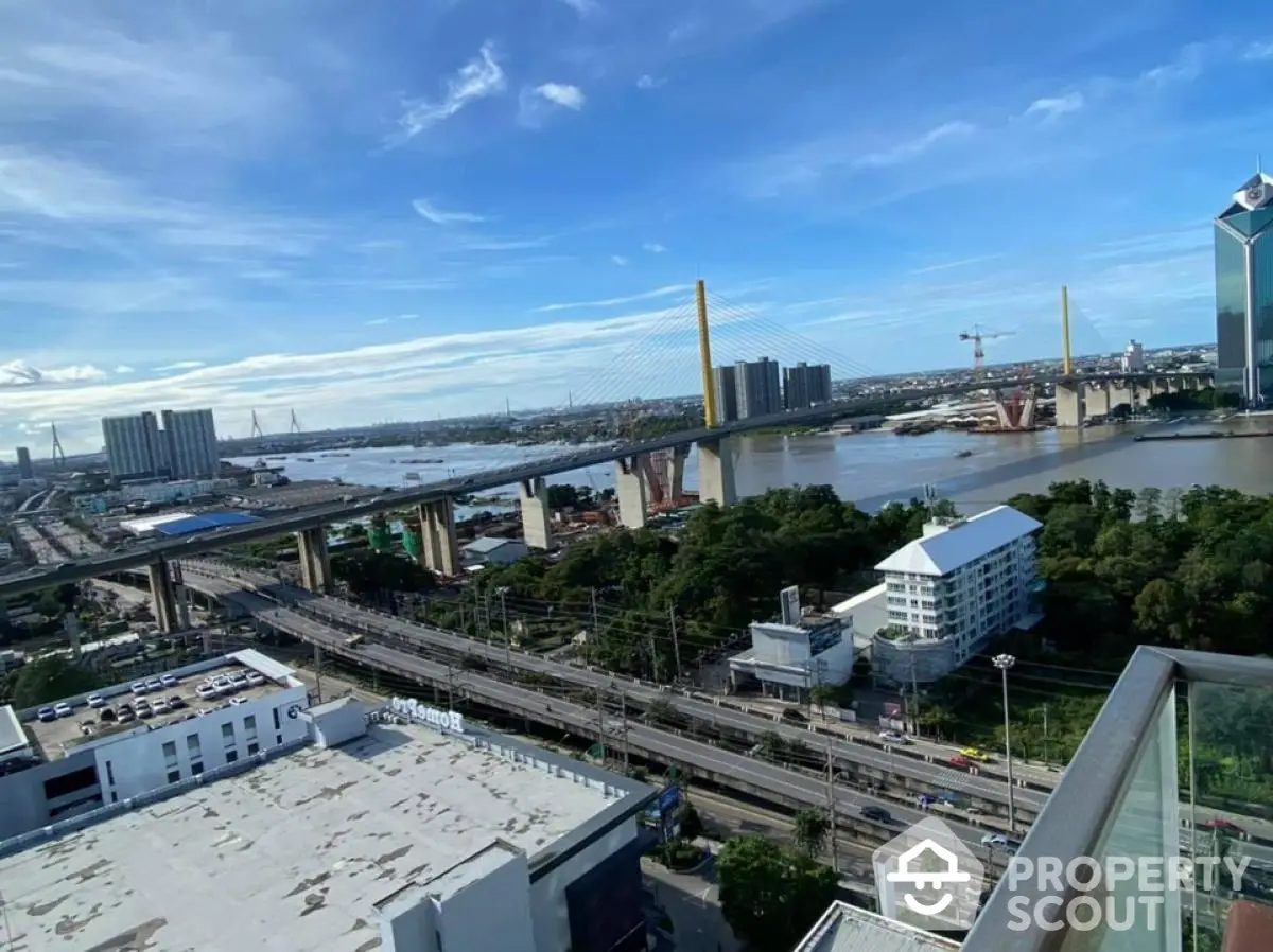 Stunning cityscape view from a high-rise balcony overlooking river and bridge.