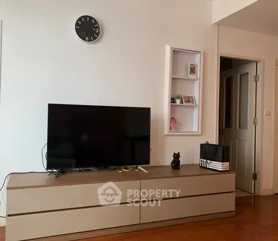 Modern living room with sleek TV stand and wall clock, showcasing minimalist decor.