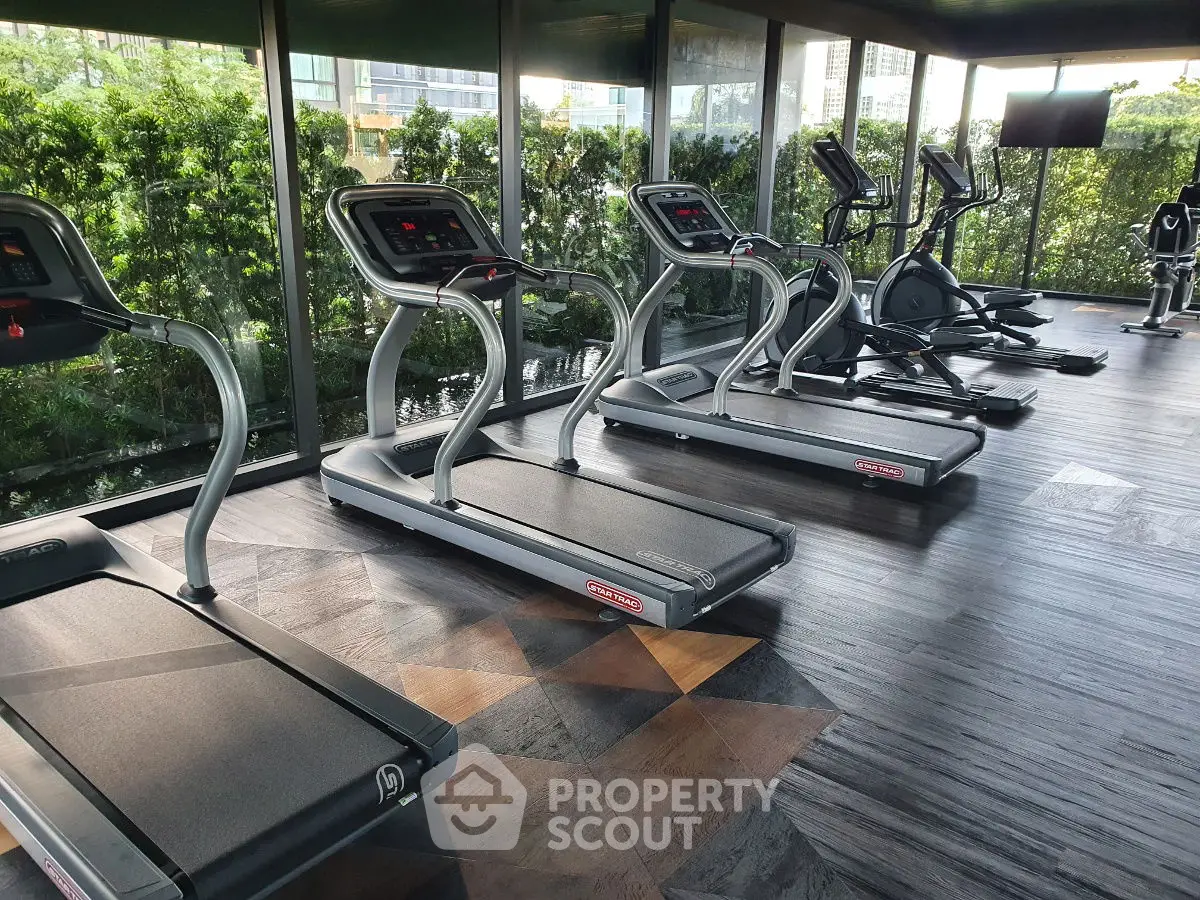Spacious gym with modern treadmills and lush greenery view, perfect for fitness enthusiasts.